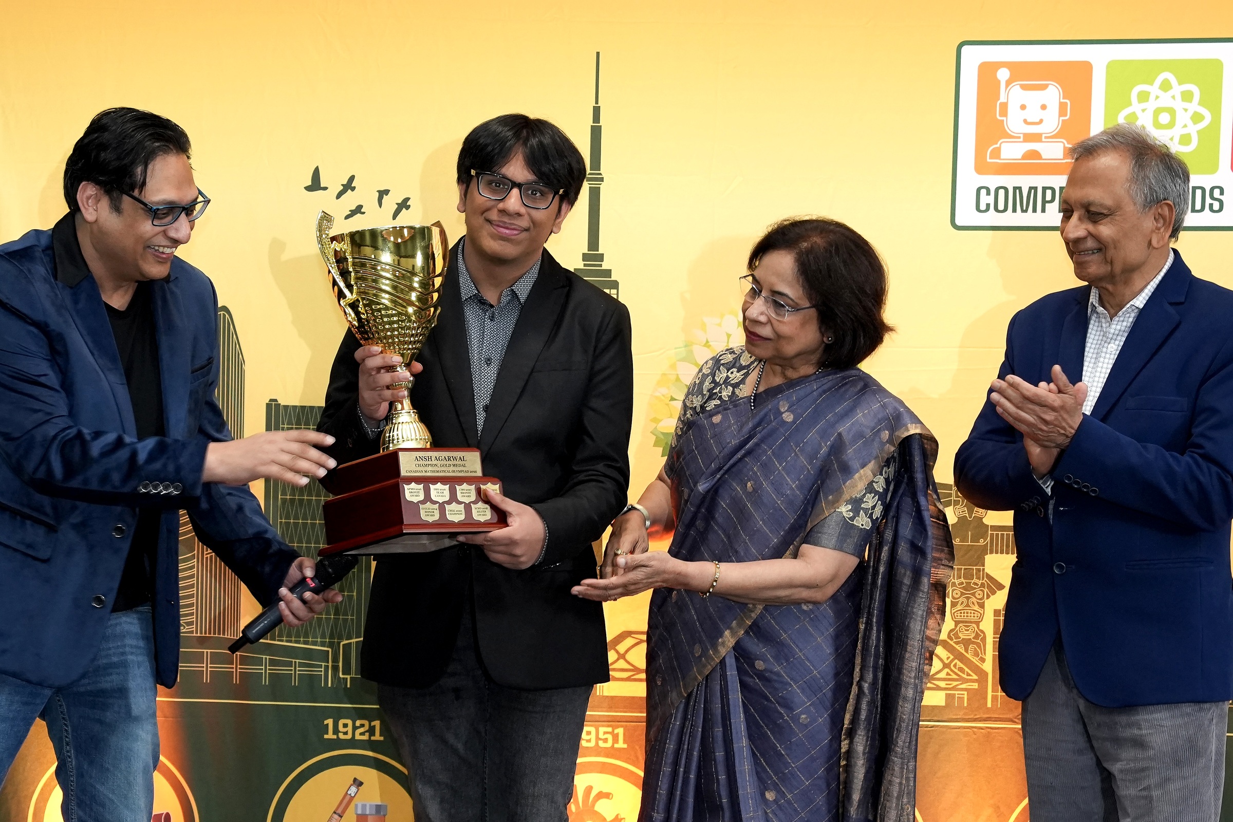 Ansh Agarwal receives the gold championship trophy.